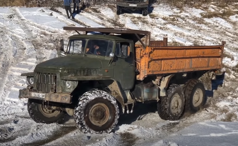 Soviet four-wheel drive trucks against a snowy mountain